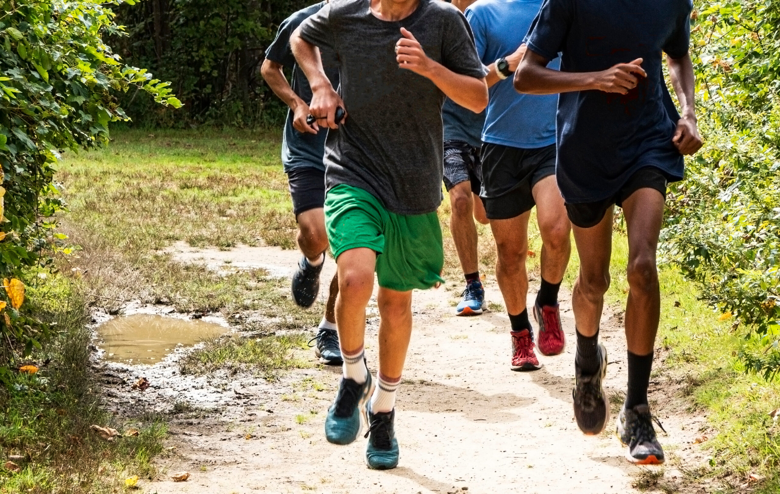 Boys run training on a dirt path in a park